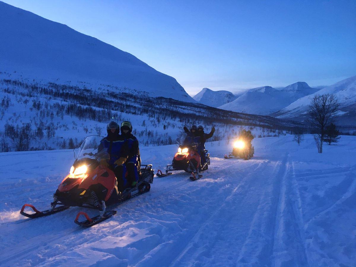 Three snowmobiles driving in the twilight
