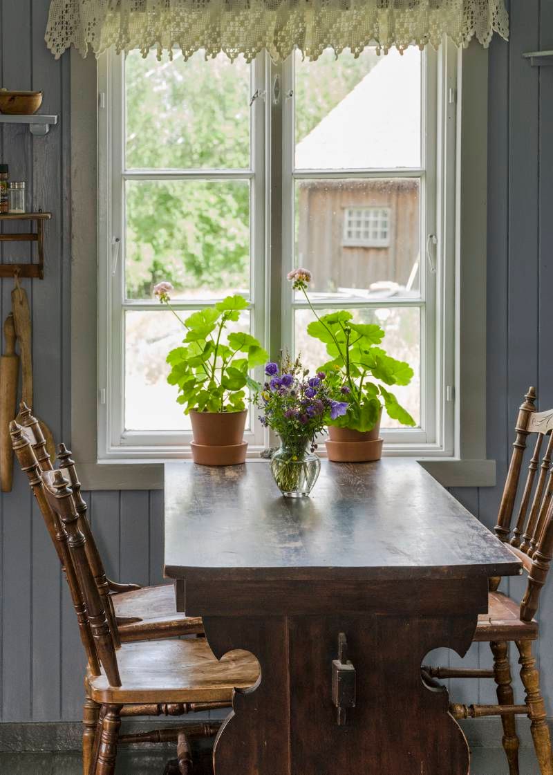 a dining table decorated with flowers by a window 
