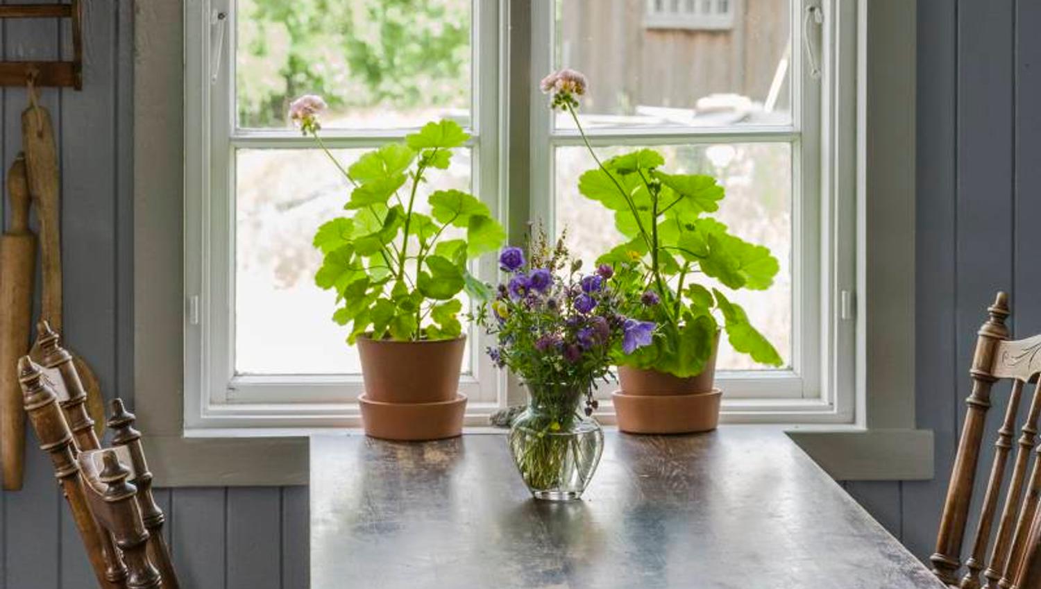 a dining table decorated with flowers by a window