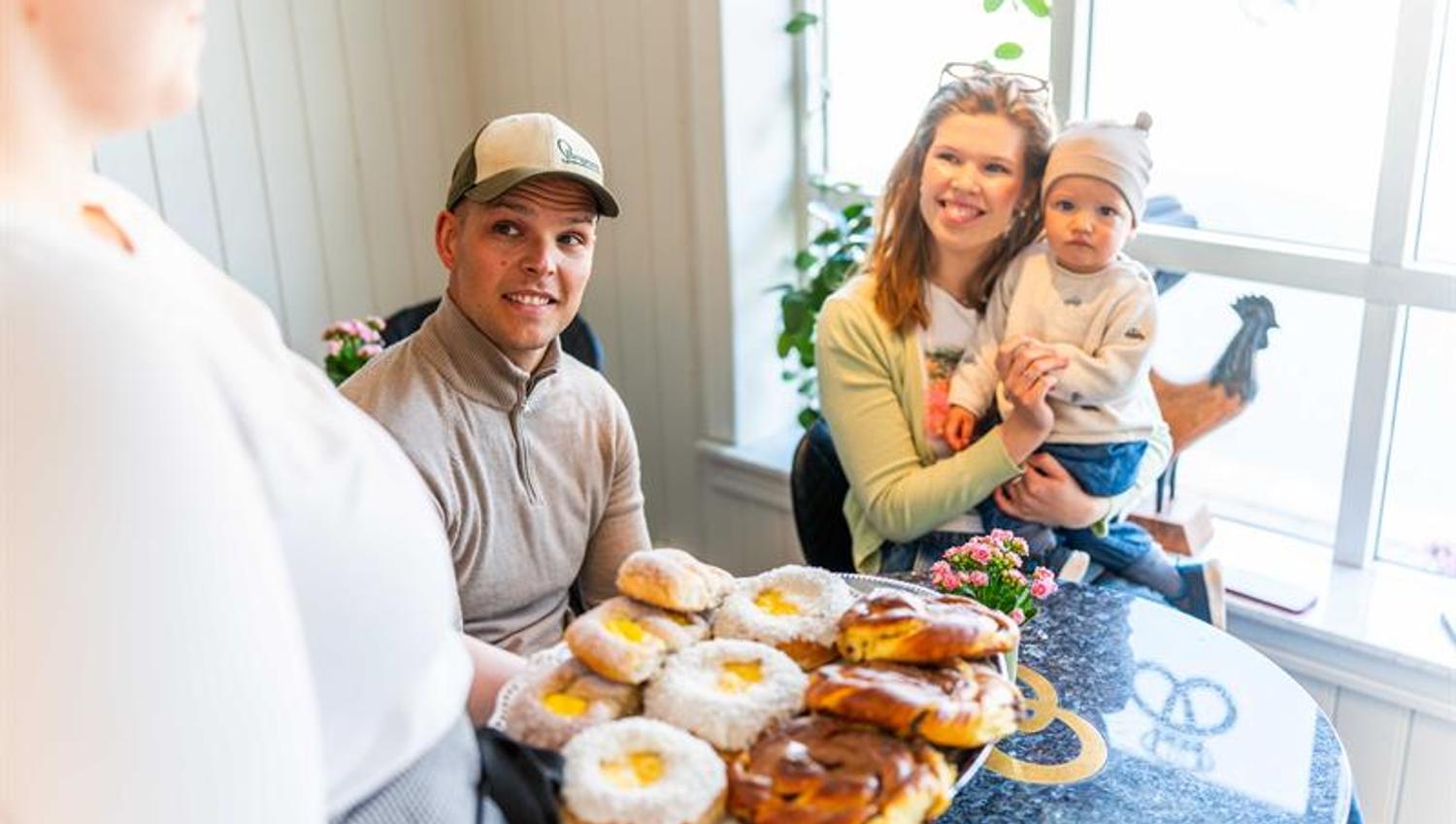To voksne og barn som sitter på cafe, blir servert skolebrød