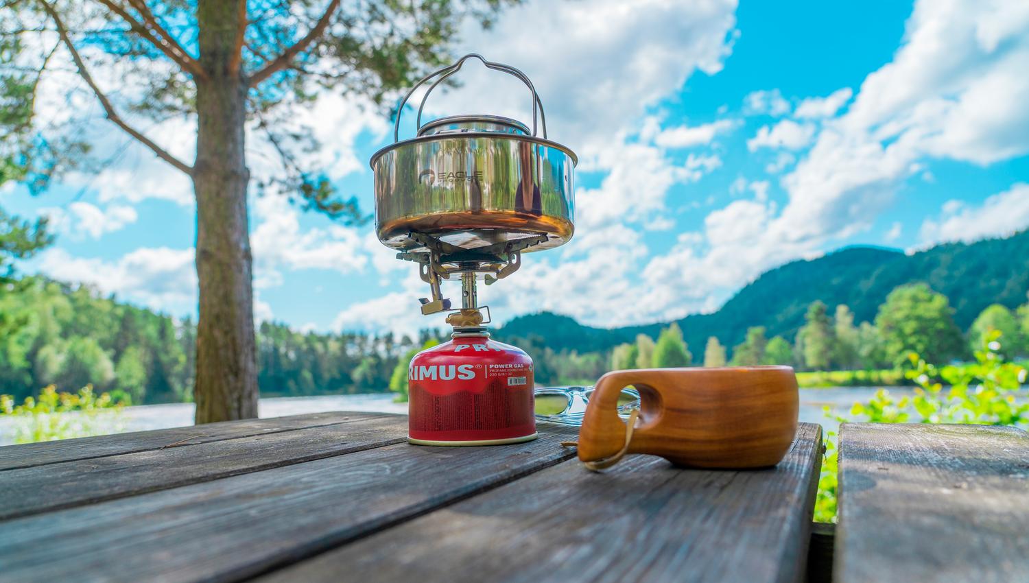 A coffee cup and a camping stove on a table outdoors at Villmarkscamp