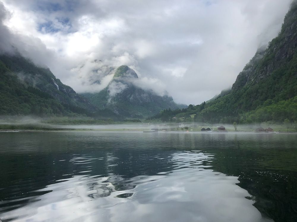 A magical atmosphere in the Hardangerfjord with low mist hanging over the water and mountains in the background.