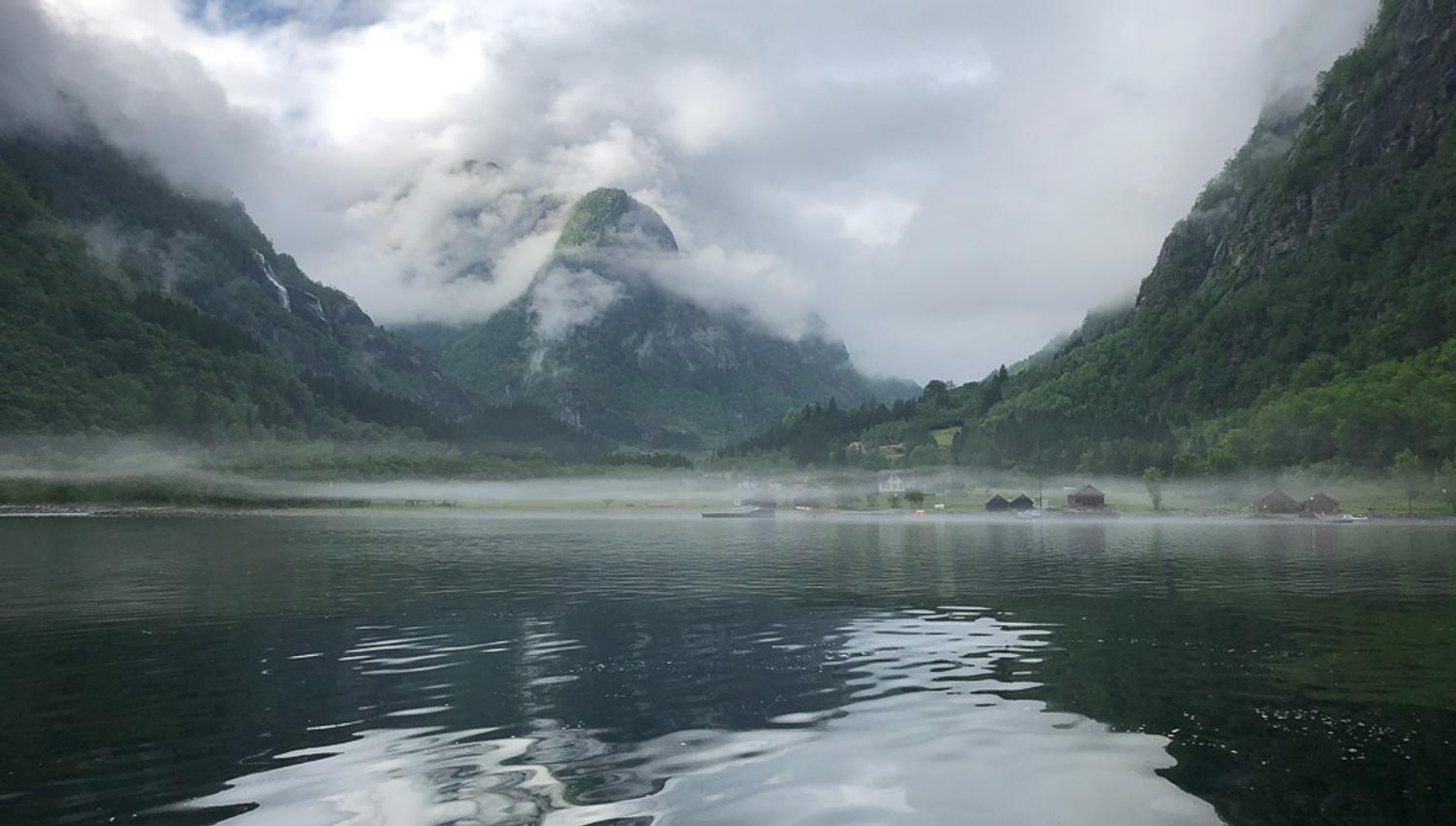 A magical atmosphere in the Hardangerfjord with low mist hanging over the water and mountains in the background.