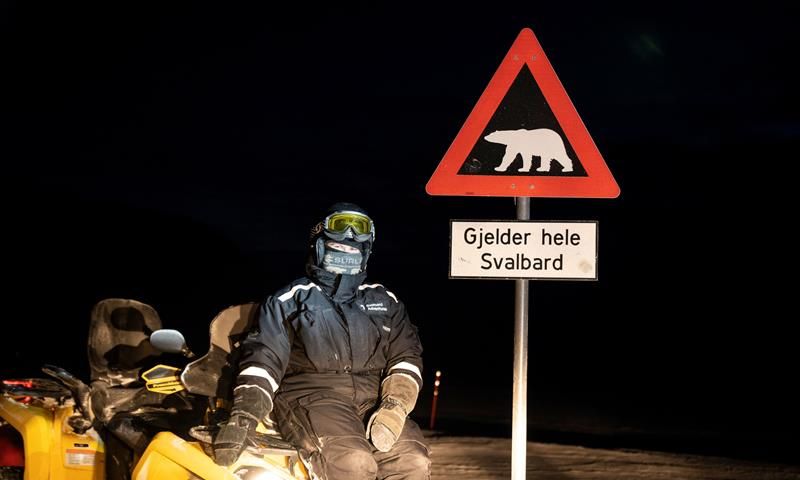 En person sitter på en ATV ved siden av isbjørnskiltet