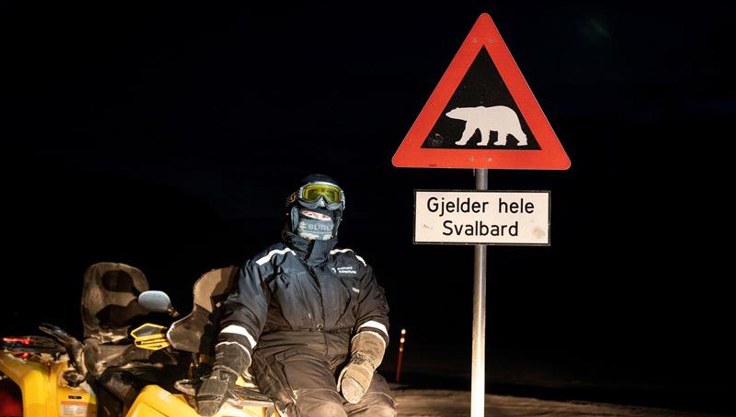 En person sitter på en ATV ved siden av isbjørnskiltet