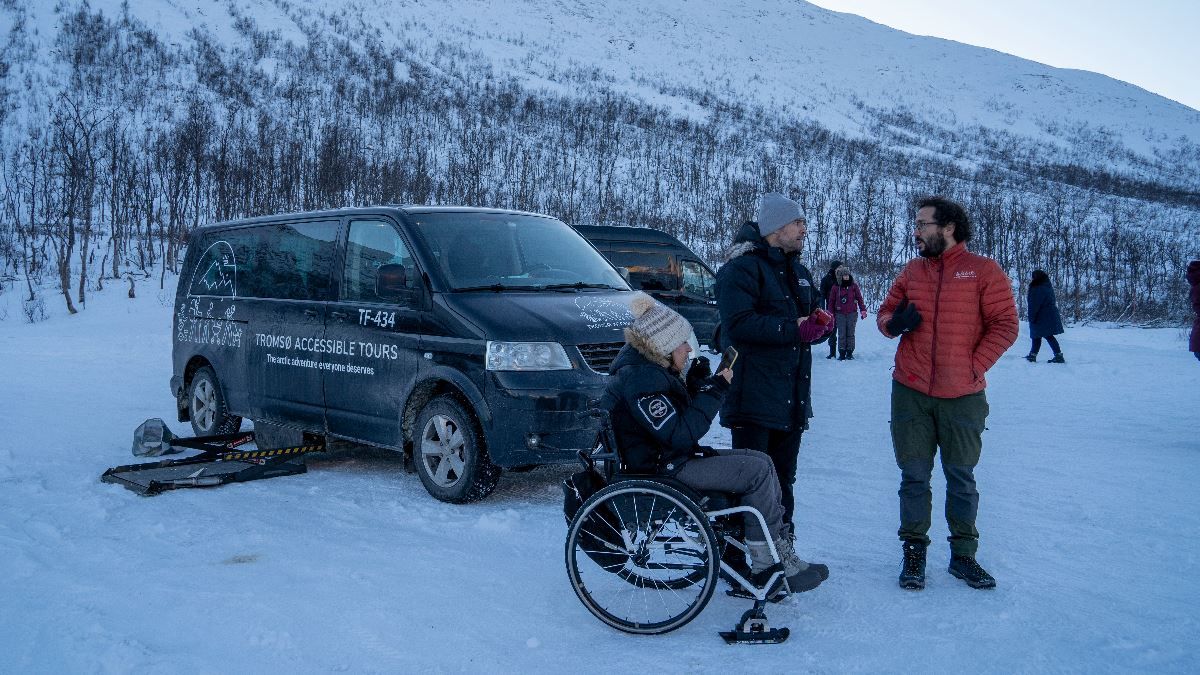 A guide and two guests besides the minivan