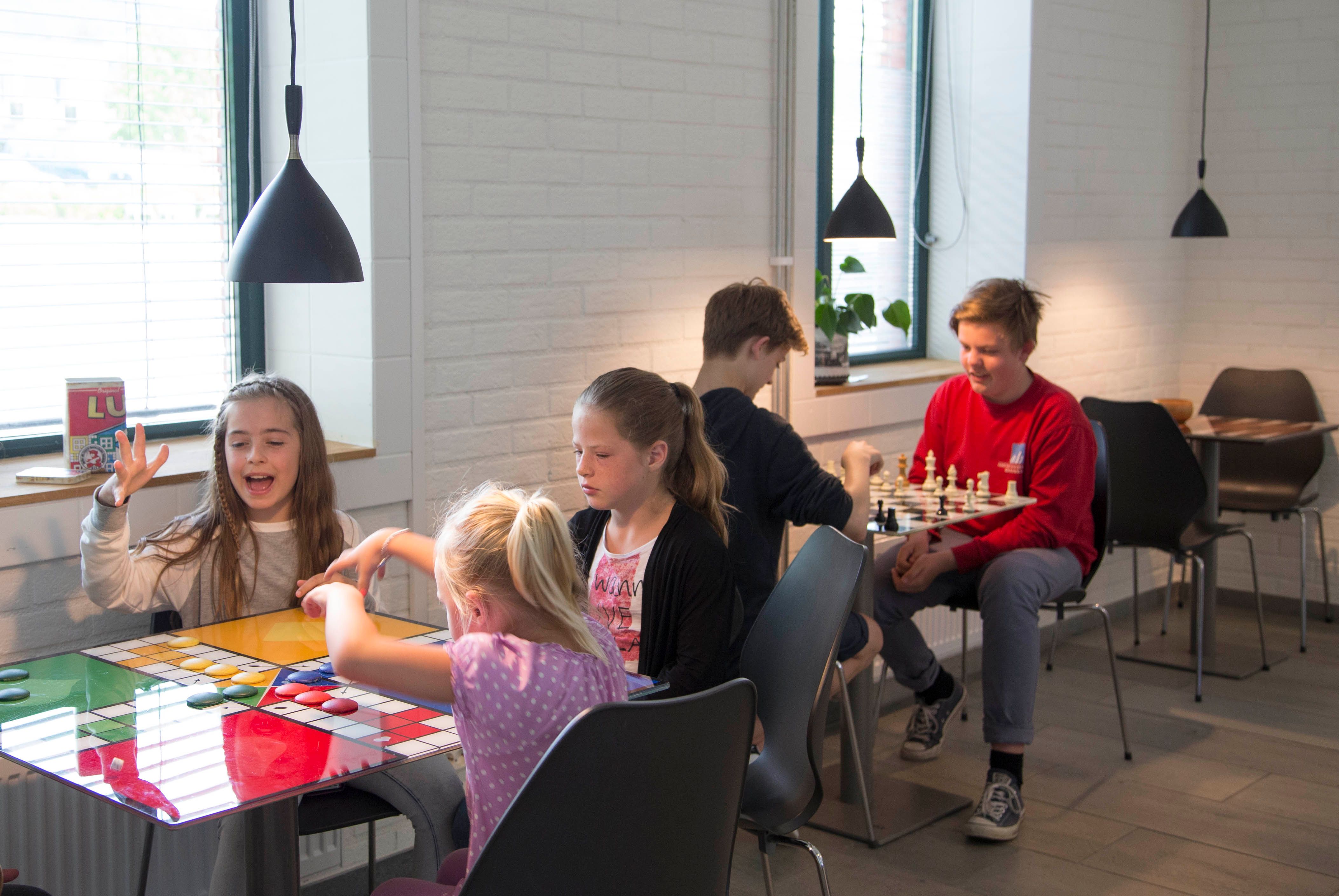 Kids and youths playing board games that are already integrated in the tabletop at Stasjonen Cafe & Restaurant