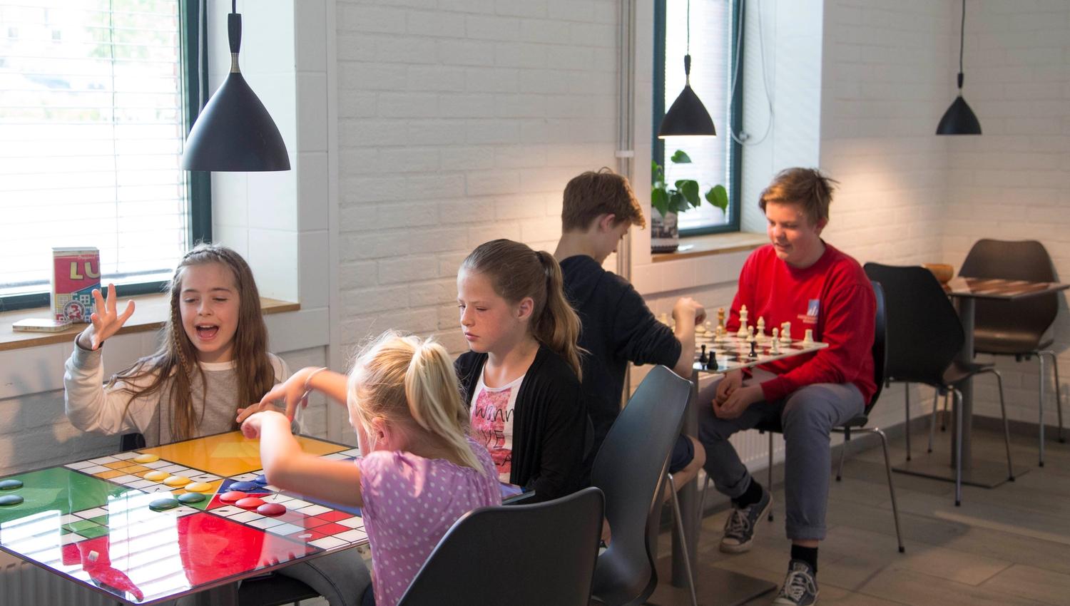 Kids and youths playing board games that are already integrated in the tabletop at Stasjonen Cafe & Restaurant