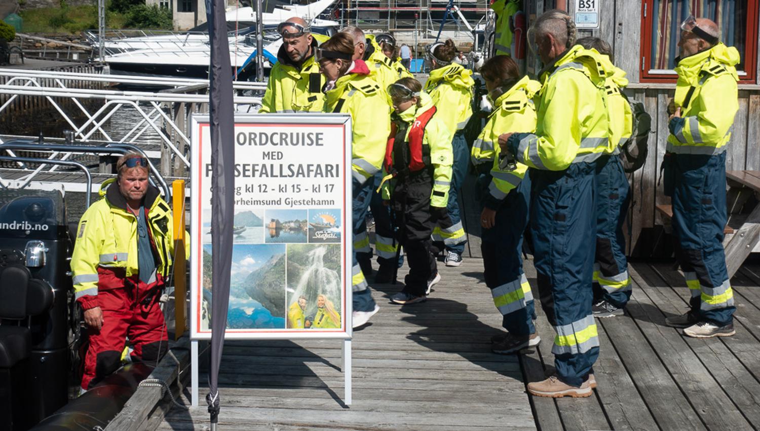 Tourists in bright yellow suits preparing for a fjord cruise and waterfall safari in Hardanger.