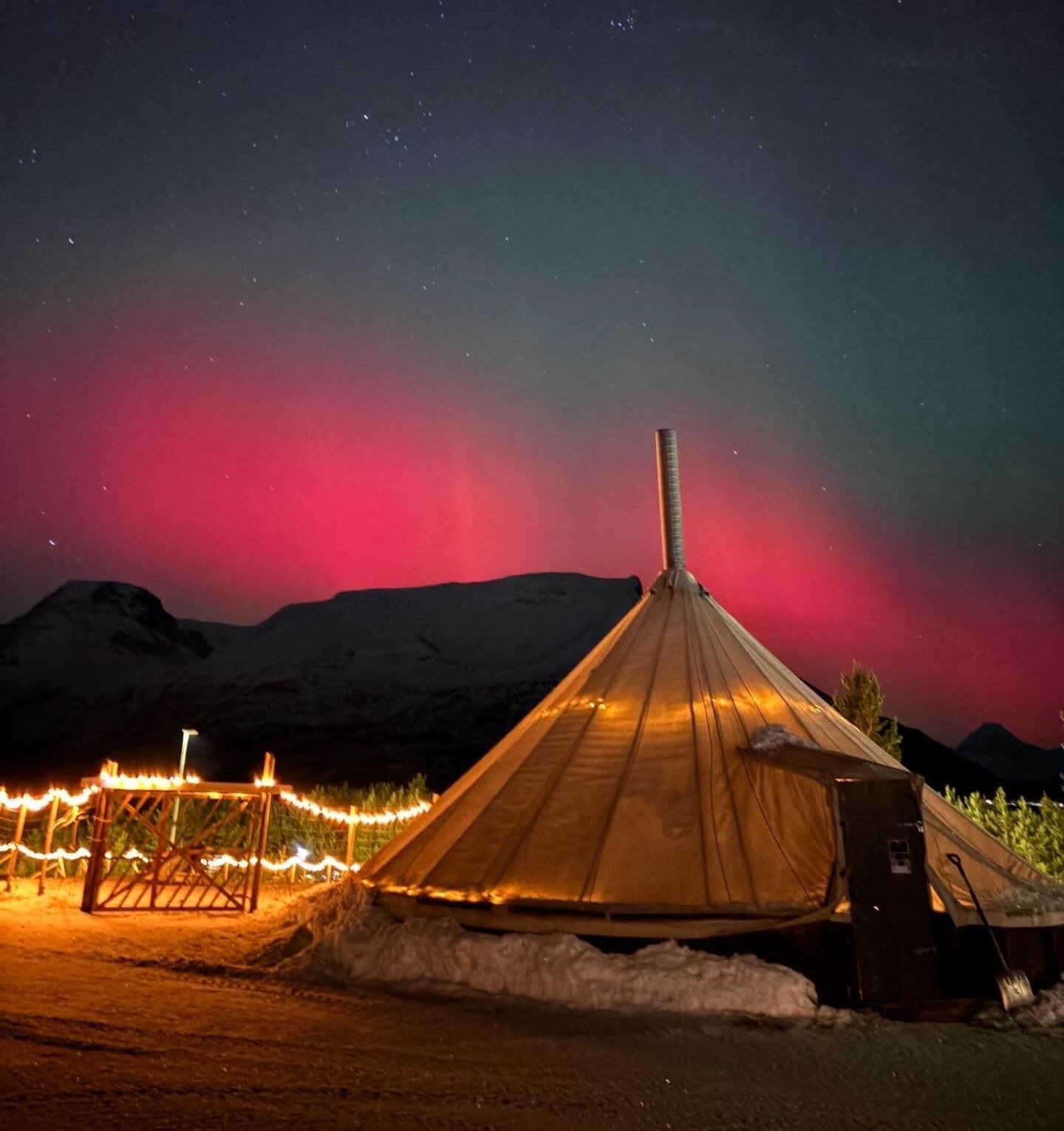 Northern lights above a lavvu in a winter landscape