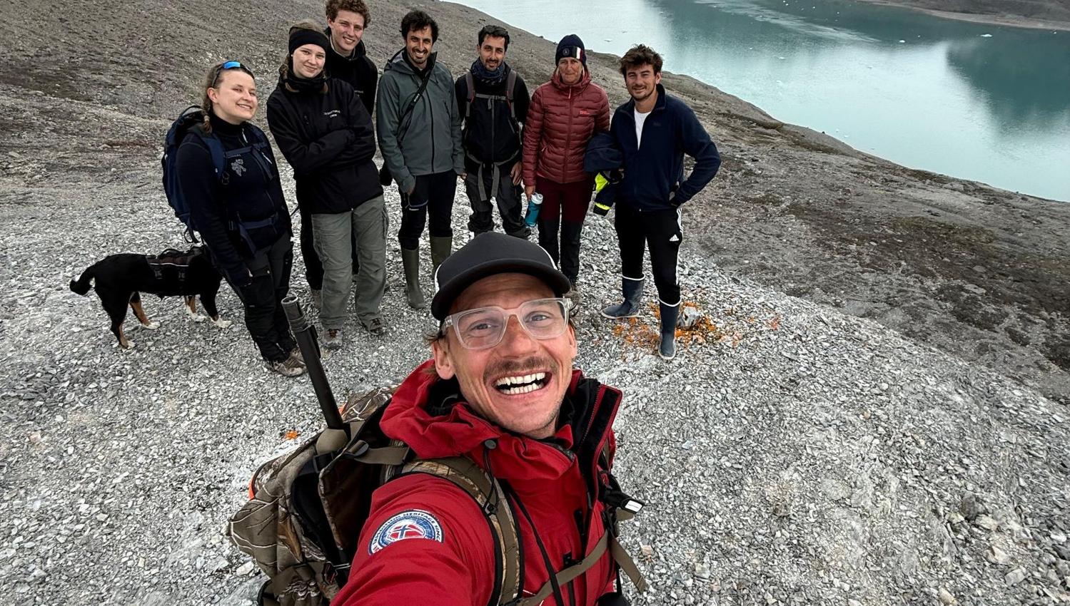 En guide tar selfie med en gruppe på tur med isbre i bakgrunnen