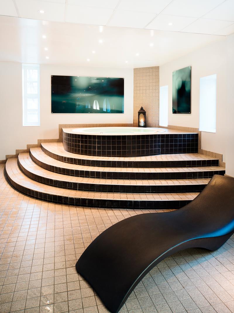 En jacuzzi med elegant, sort stol og flislagt gulv.
