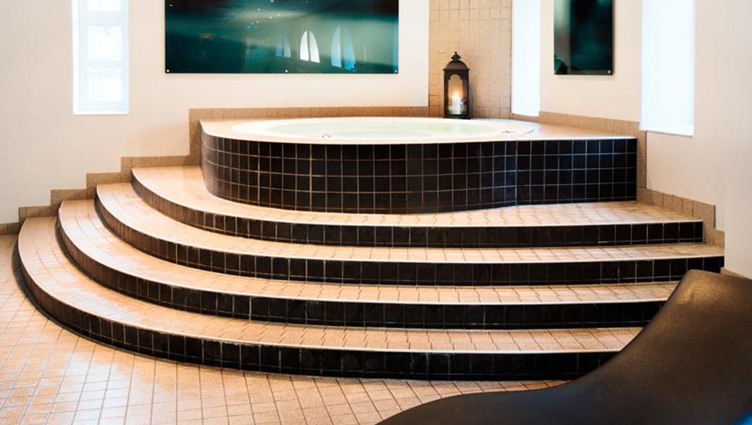 En jacuzzi med elegant, sort stol og flislagt gulv.