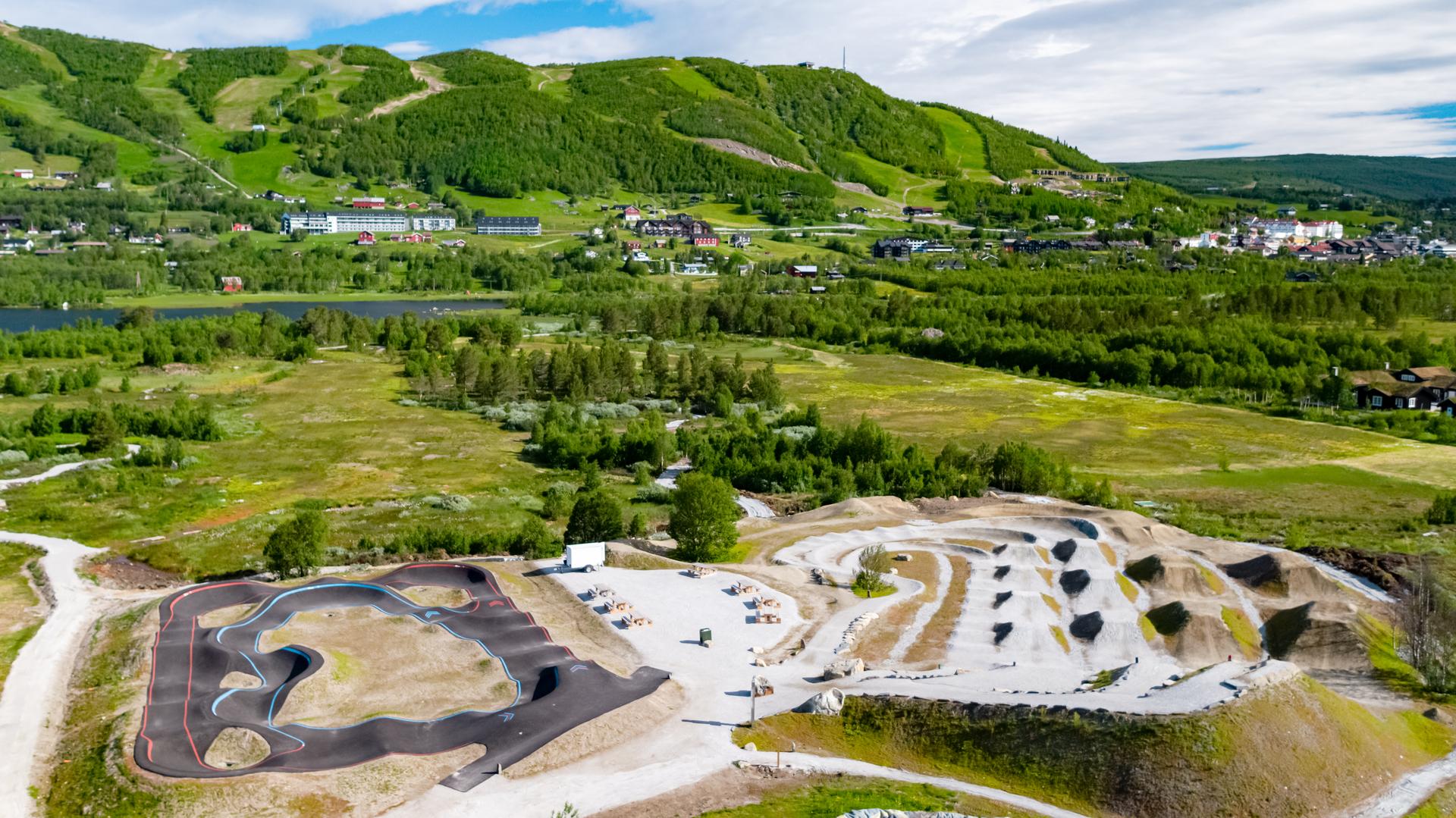 Vestlia Bike Park with pump track and jump lines and the green alpine slopes with the Geilo city centre in the background.