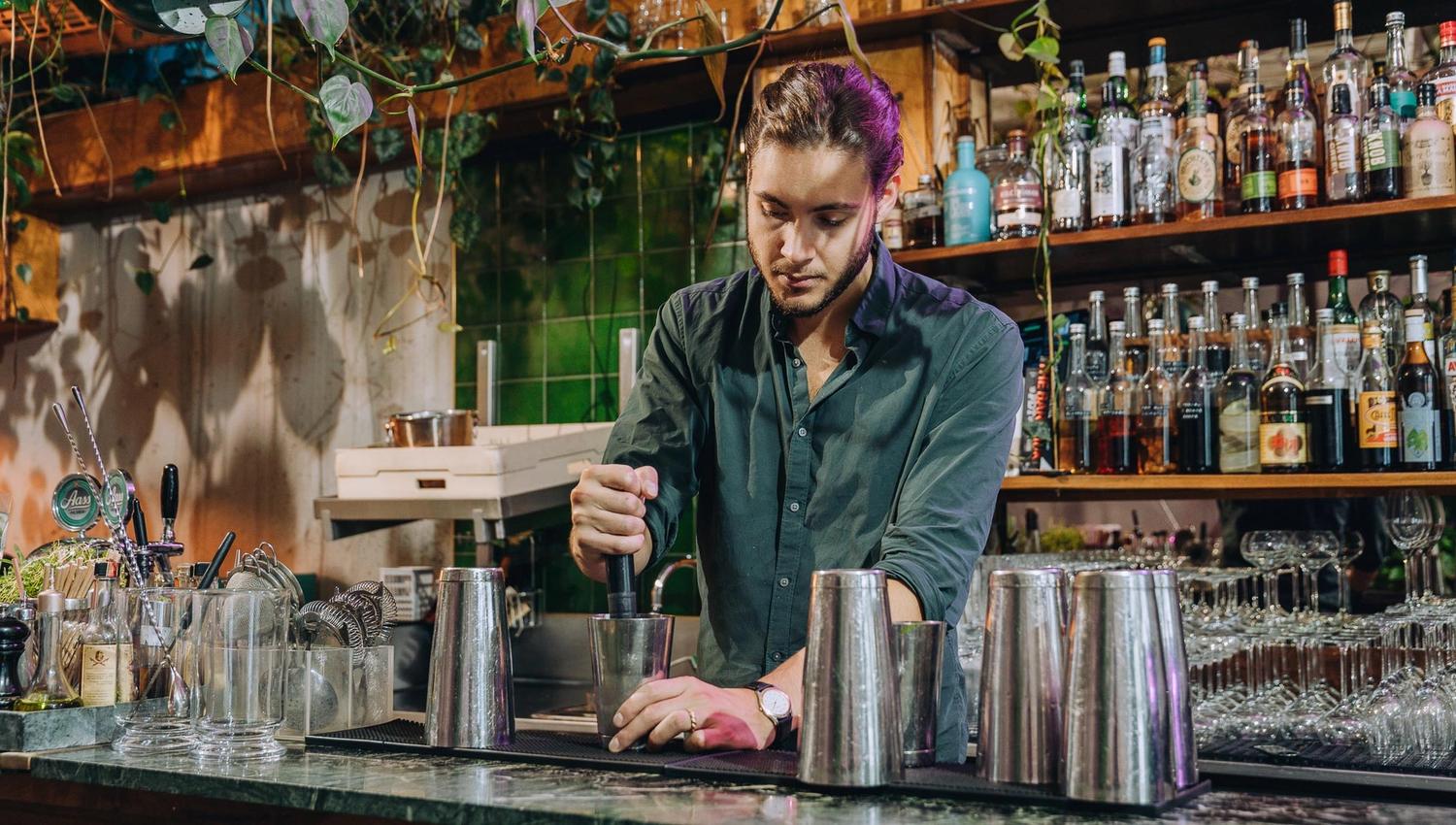 Bartender bak baren som mikser en drink