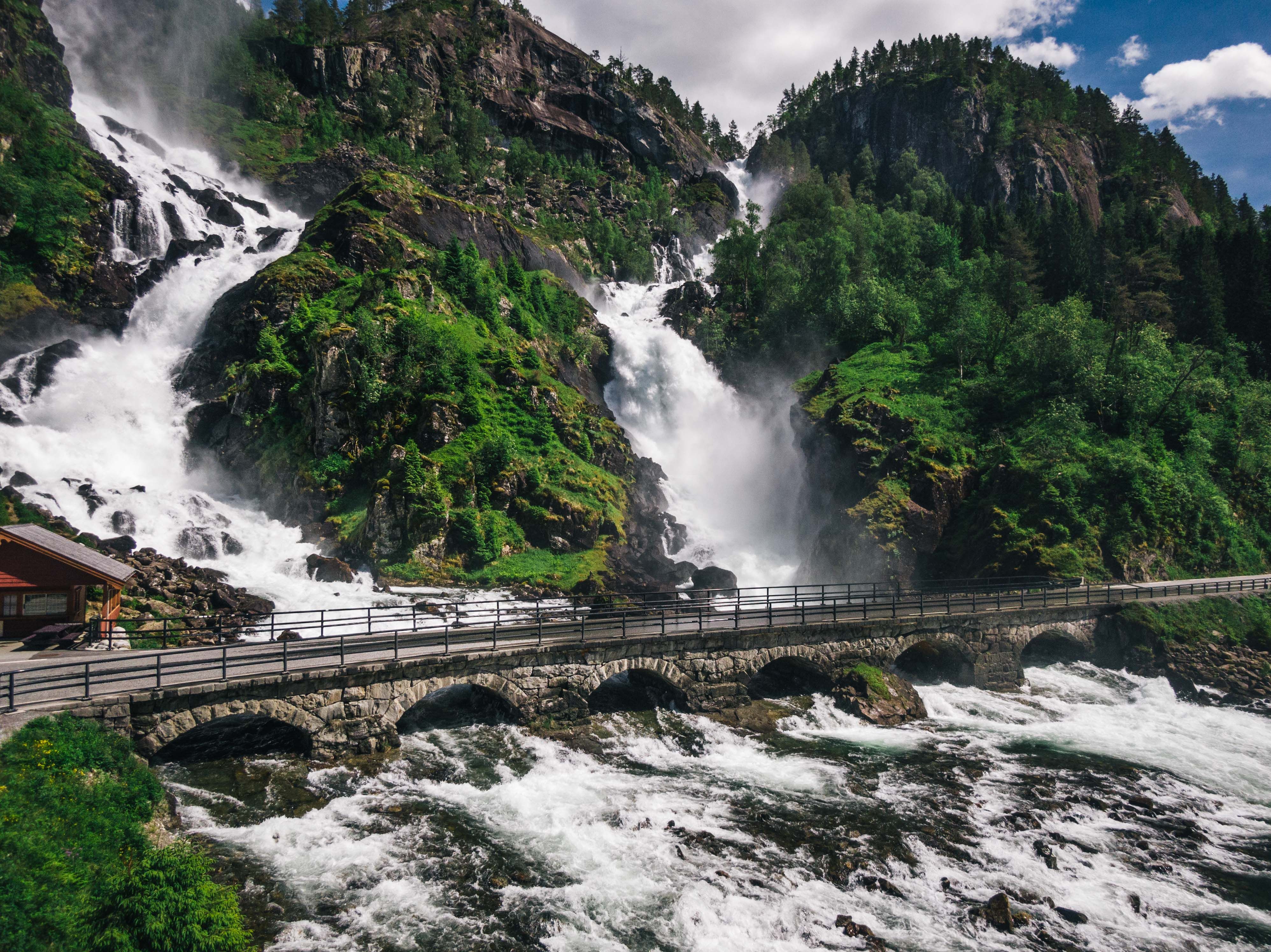 Mighty Låtefoss with a bridge over the rushing river surrounded by lush vegetation.