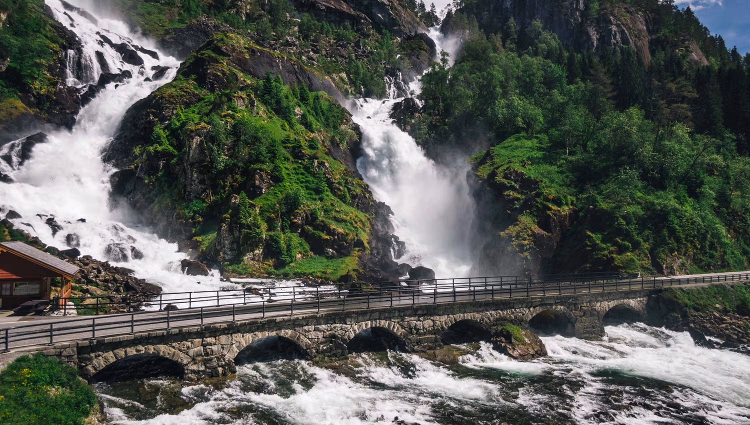Mighty Låtefoss with a bridge over the rushing river surrounded by lush vegetation.