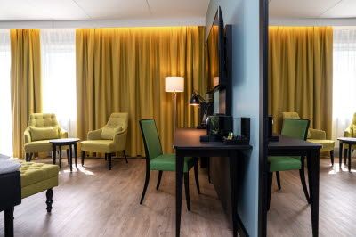 Room interior with yellow curtains, yellow armchairs, TV screen on the wall and desk.