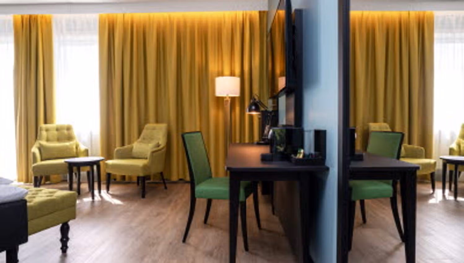 Room interior with yellow curtains, yellow armchairs, TV screen on the wall and desk.
