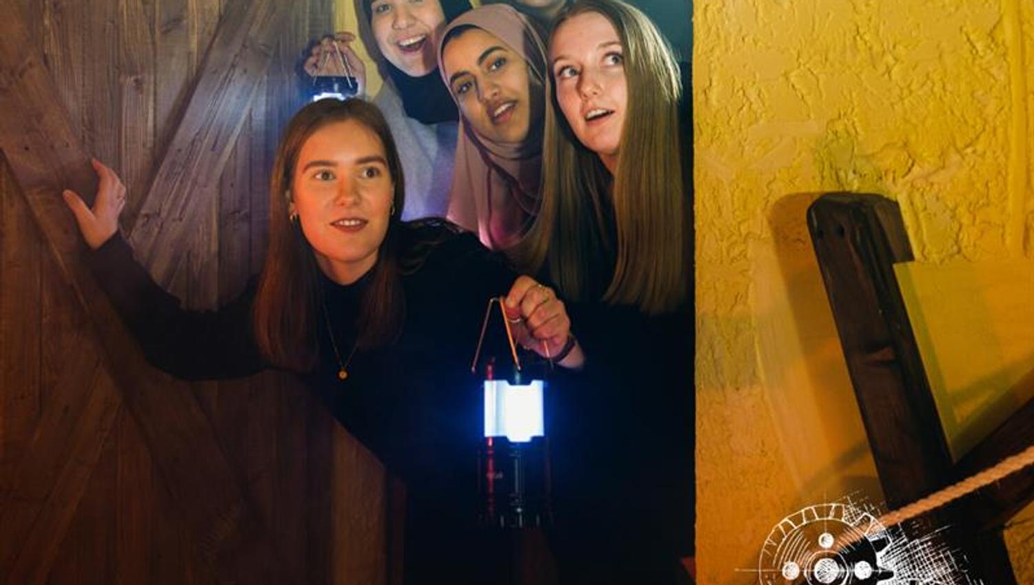 a group of women peering excitedly through a doorway with lanterns in hand