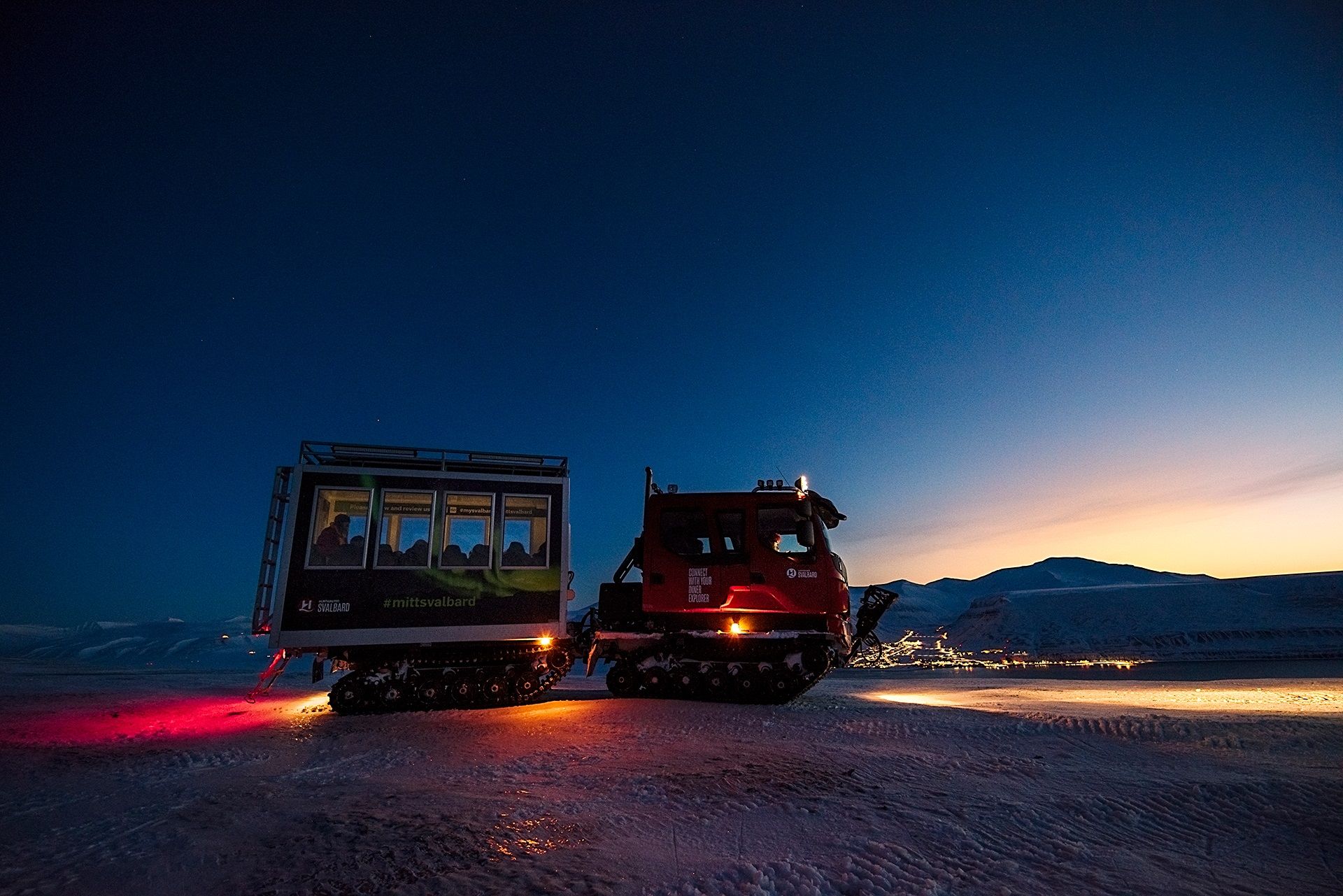 Beltevogn ute i felt med Longyearbyen i bakgrunnen