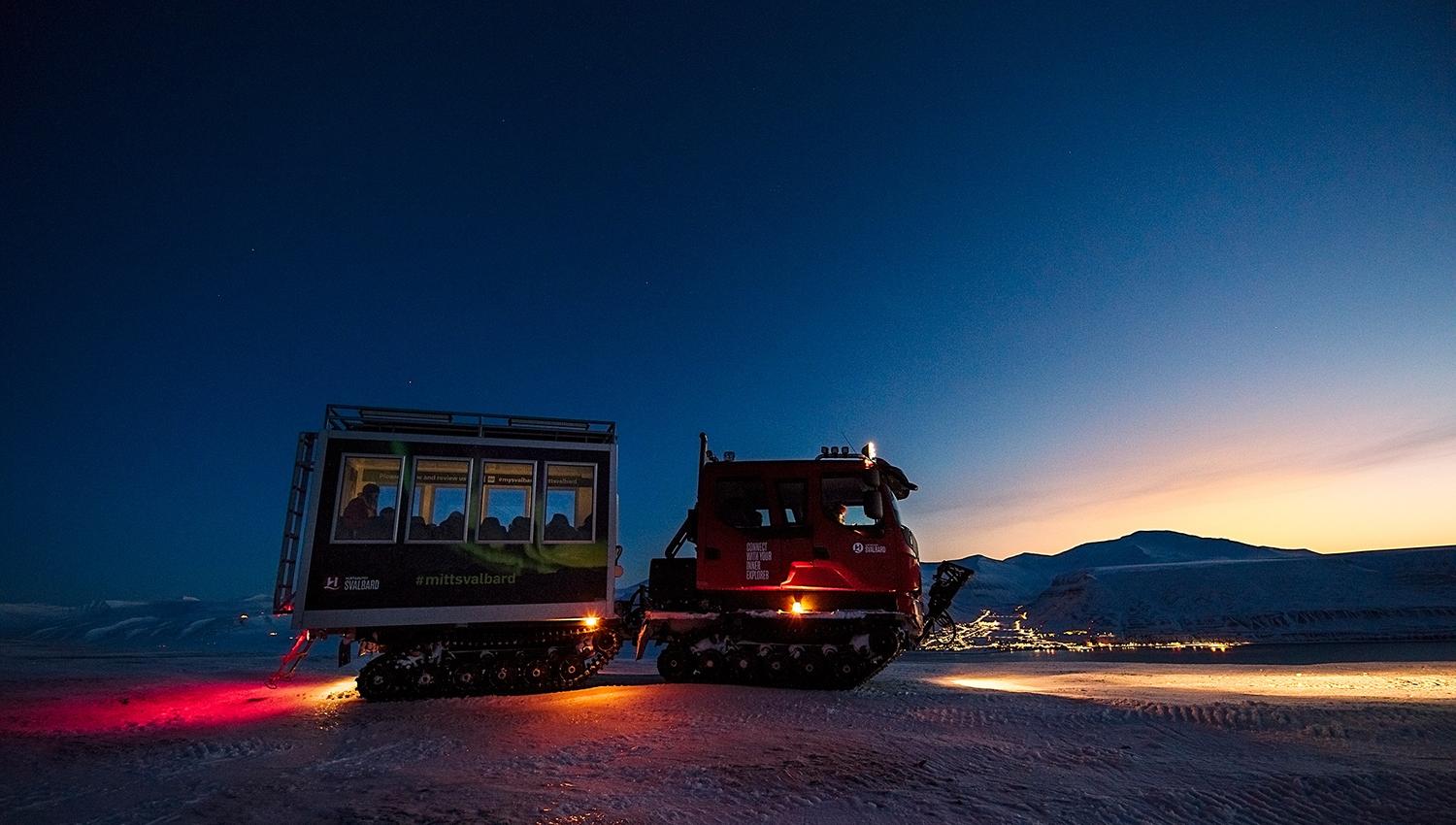 Beltevogn ute i felt med Longyearbyen i bakgrunnen