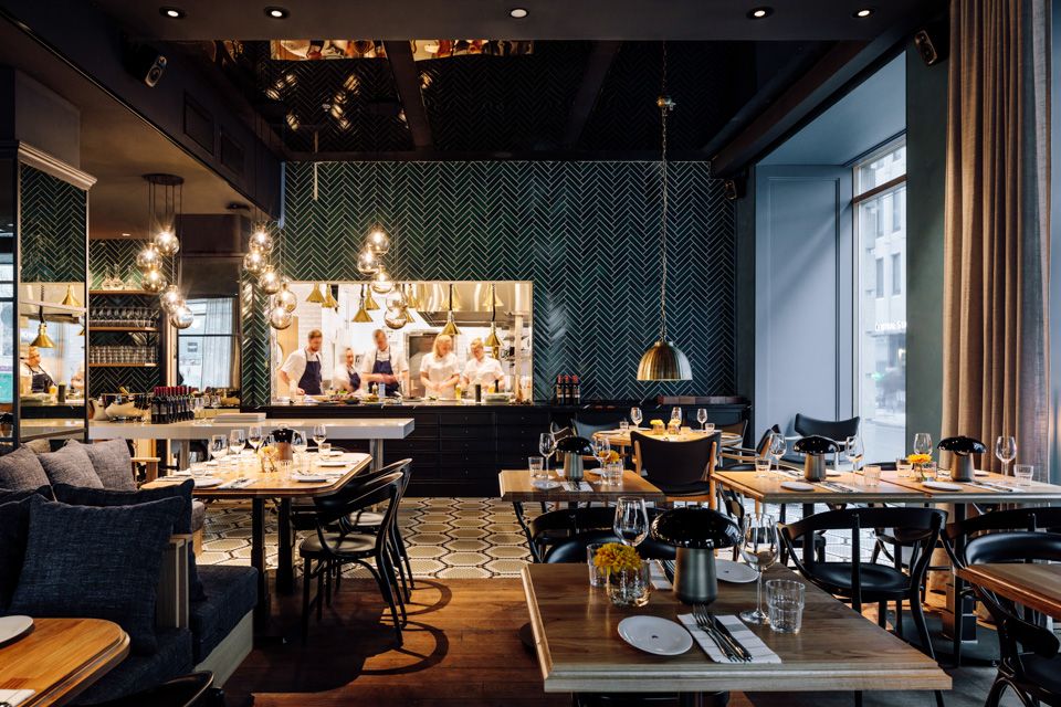 Restaurant Atlas - interior photo. Set tables with chairs, seating section, hanging ceiling lamps and the kitchen in the background.
