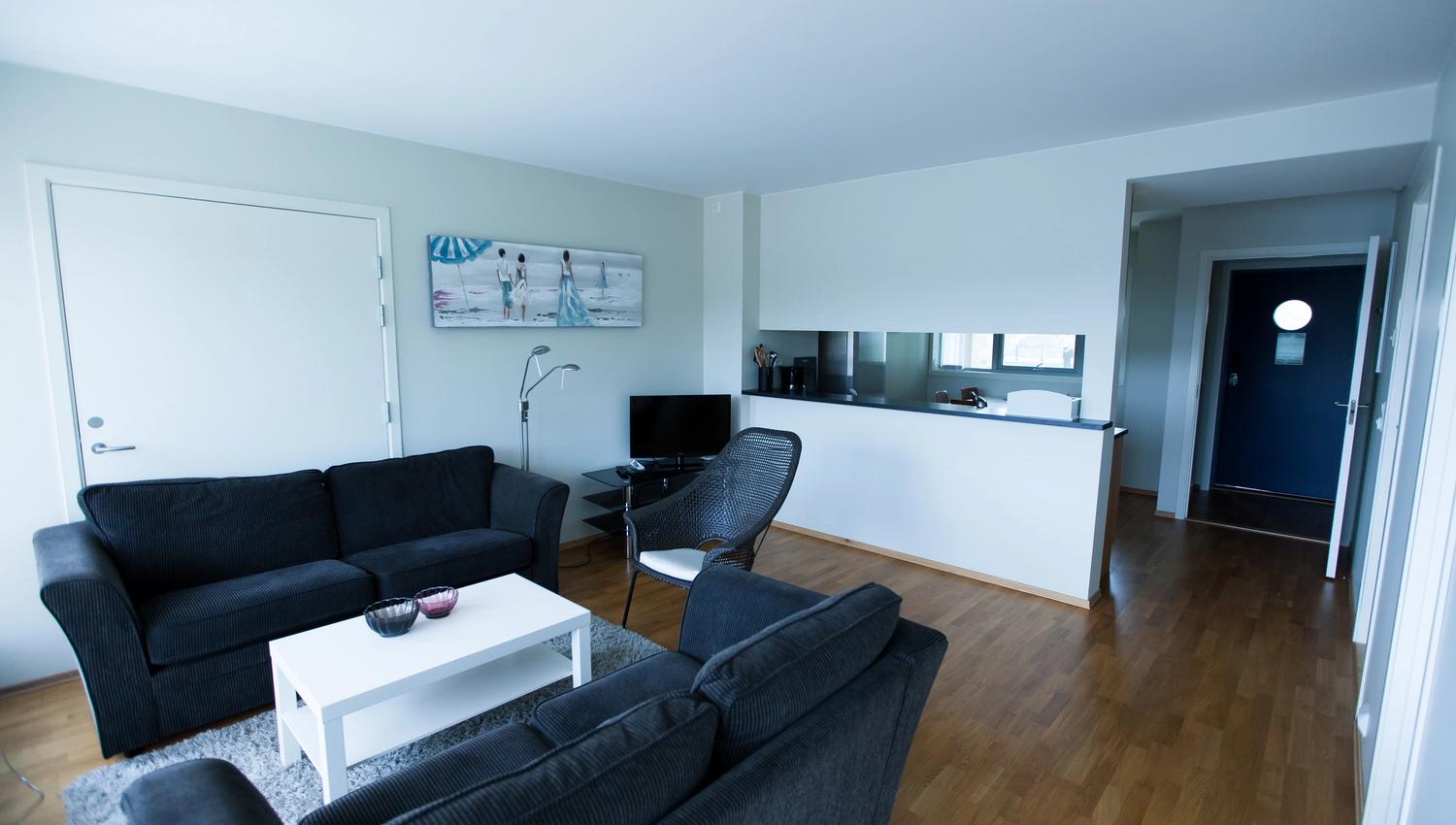 Lindesnes Havhotell - Stua til hotellrommet, et par med svarte toseter sofa.