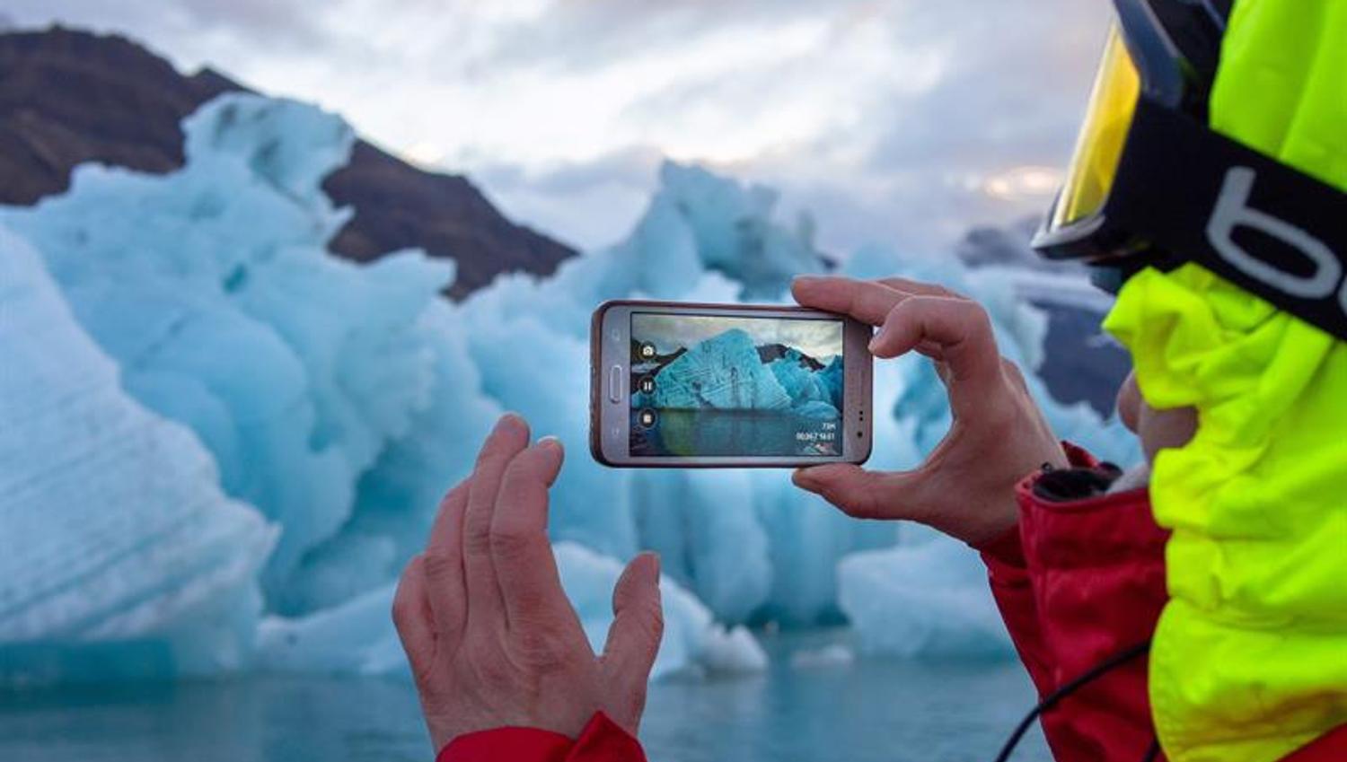 A person taking photos of icebergs