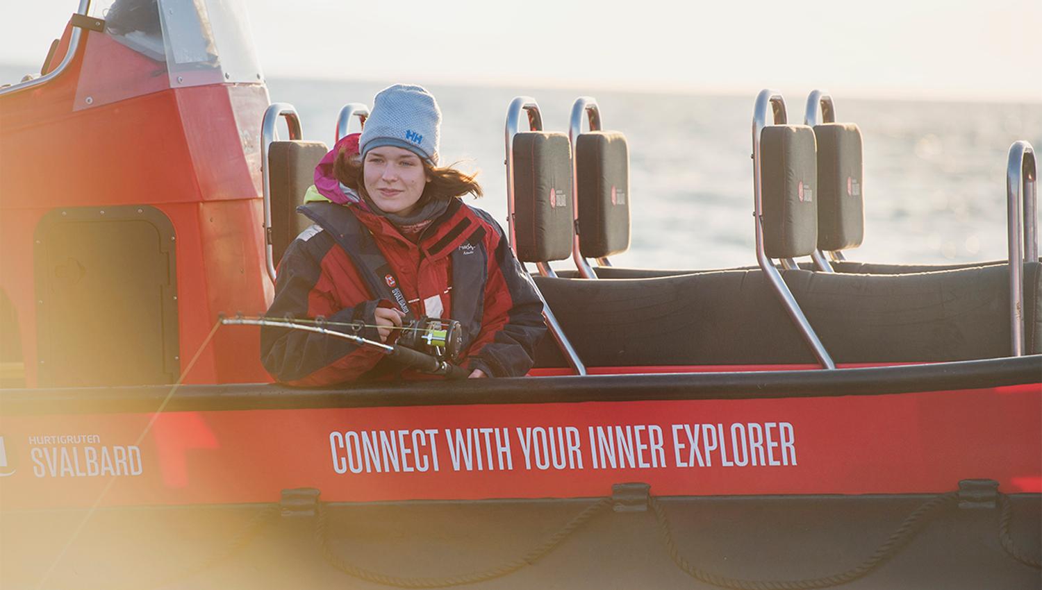En gjest som sitter i en RIB båt med en fiskestang og fisker fra båten