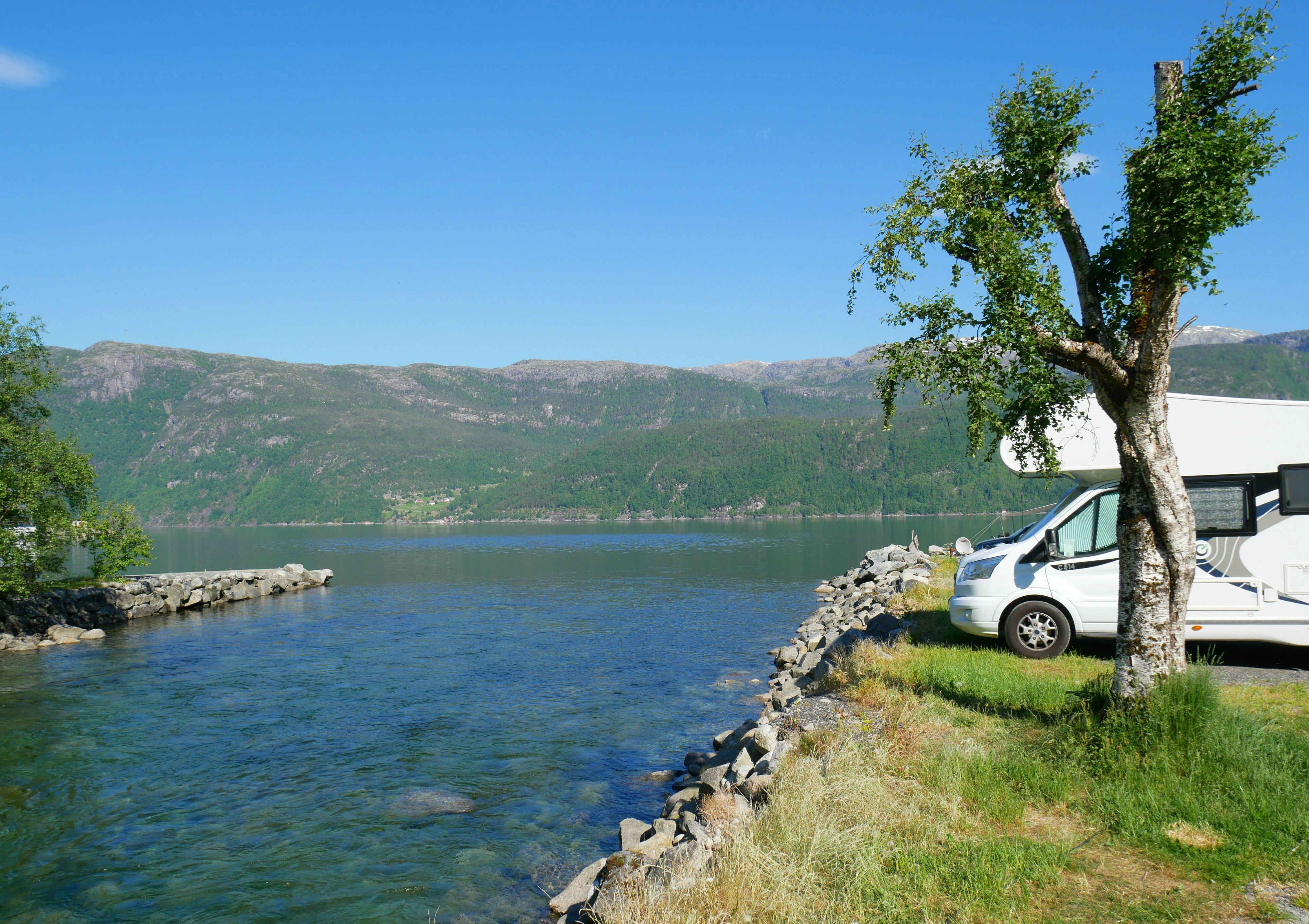 Bobil parkert ved elva med utsikt mot fjorden og dei grøne fjella i Hardanger.
