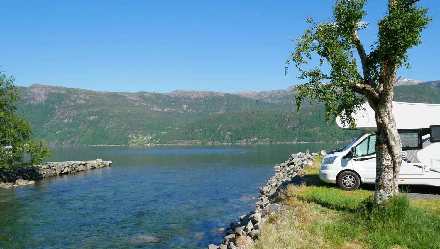 Bobil parkert ved elva med utsikt mot fjorden og dei grøne fjella i Hardanger.