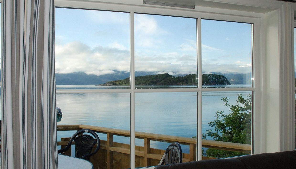 Living room view from Naustferie overlooking the fjord and islands of Hardanger under calm skies.