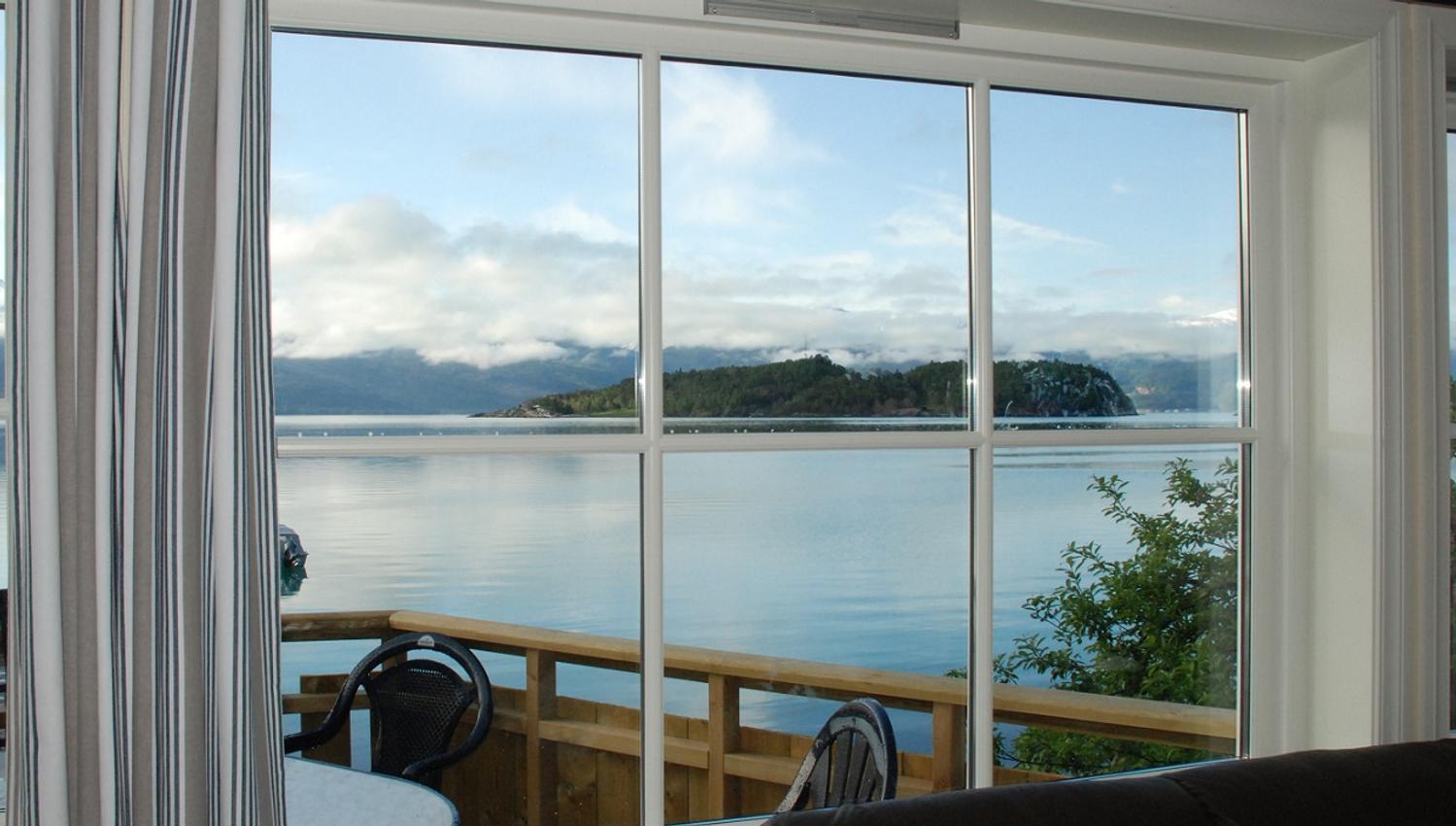 Living room view from Naustferie overlooking the fjord and islands of Hardanger under calm skies.