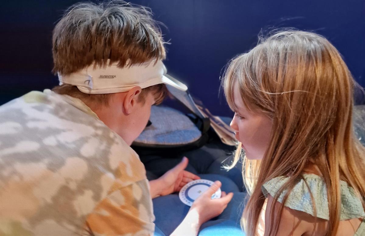 Two children taking part in an outdoor activity with a bowl.