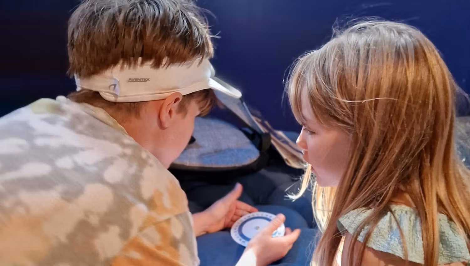 Two children taking part in an outdoor activity with a bowl.