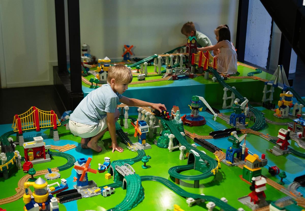 Children playing with a model railway display on a table.