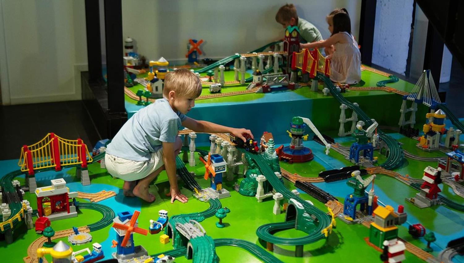 Children playing with a model railway display on a table.
