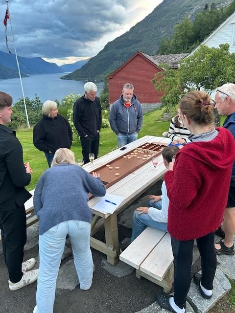 A group of guests playing a traditional board game outdoors in the fresh fjord air at Jaastad Gjestetun.