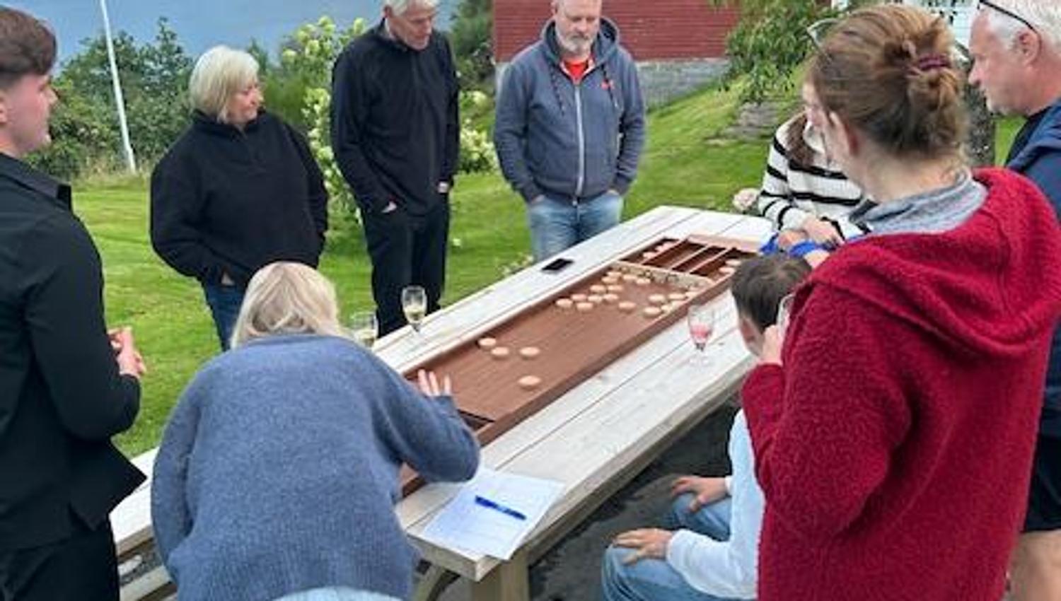 A group of guests playing a traditional board game outdoors in the fresh fjord air at Jaastad Gjestetun.