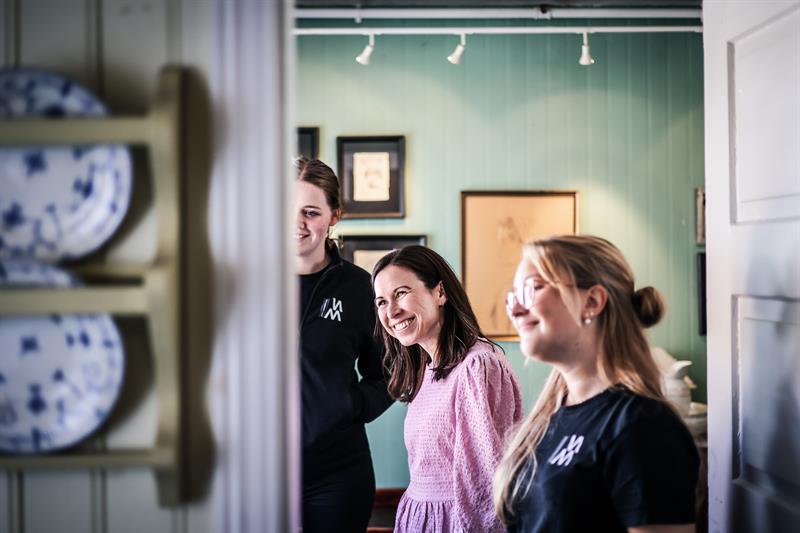 Two employees and a customer are smiling and looking at something.