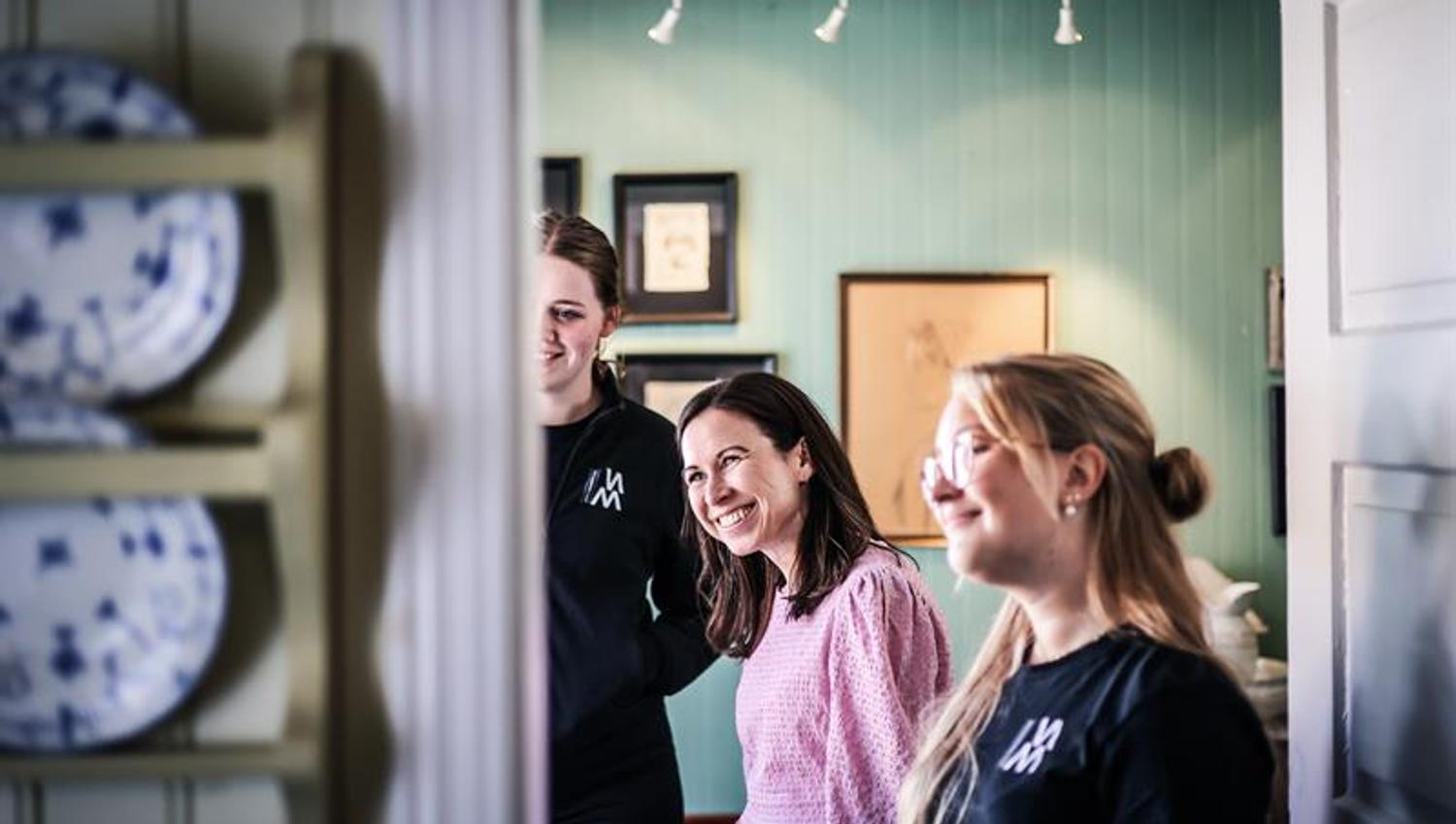 Two employees and a customer are smiling and looking at something.