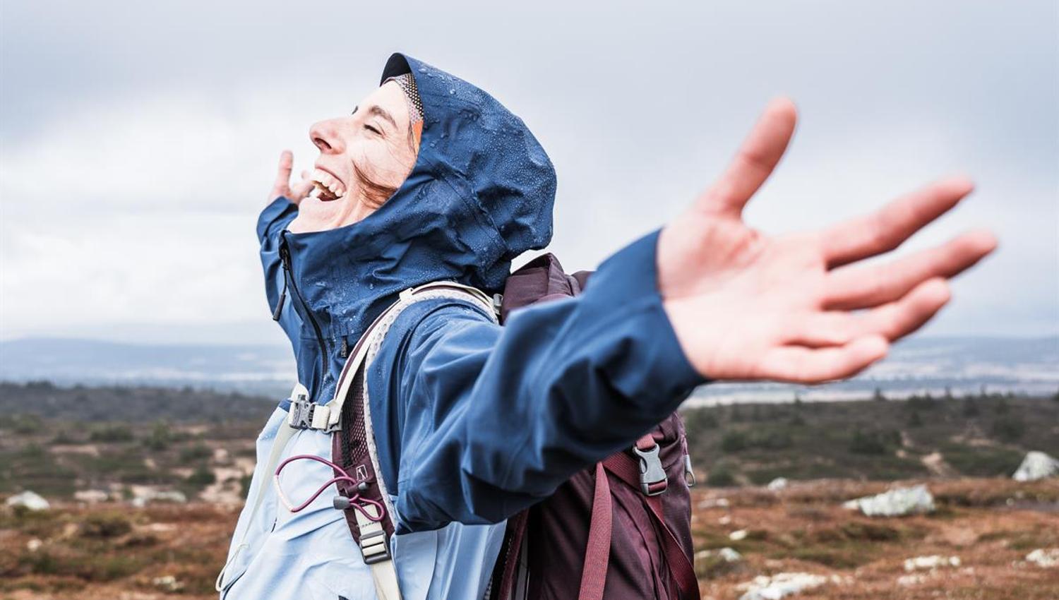 Person with arms outstretched towards open sky in the mountains