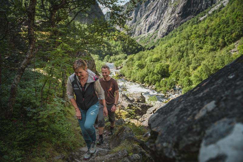 Three hikers on the path towards the new bridge below the waterfall.