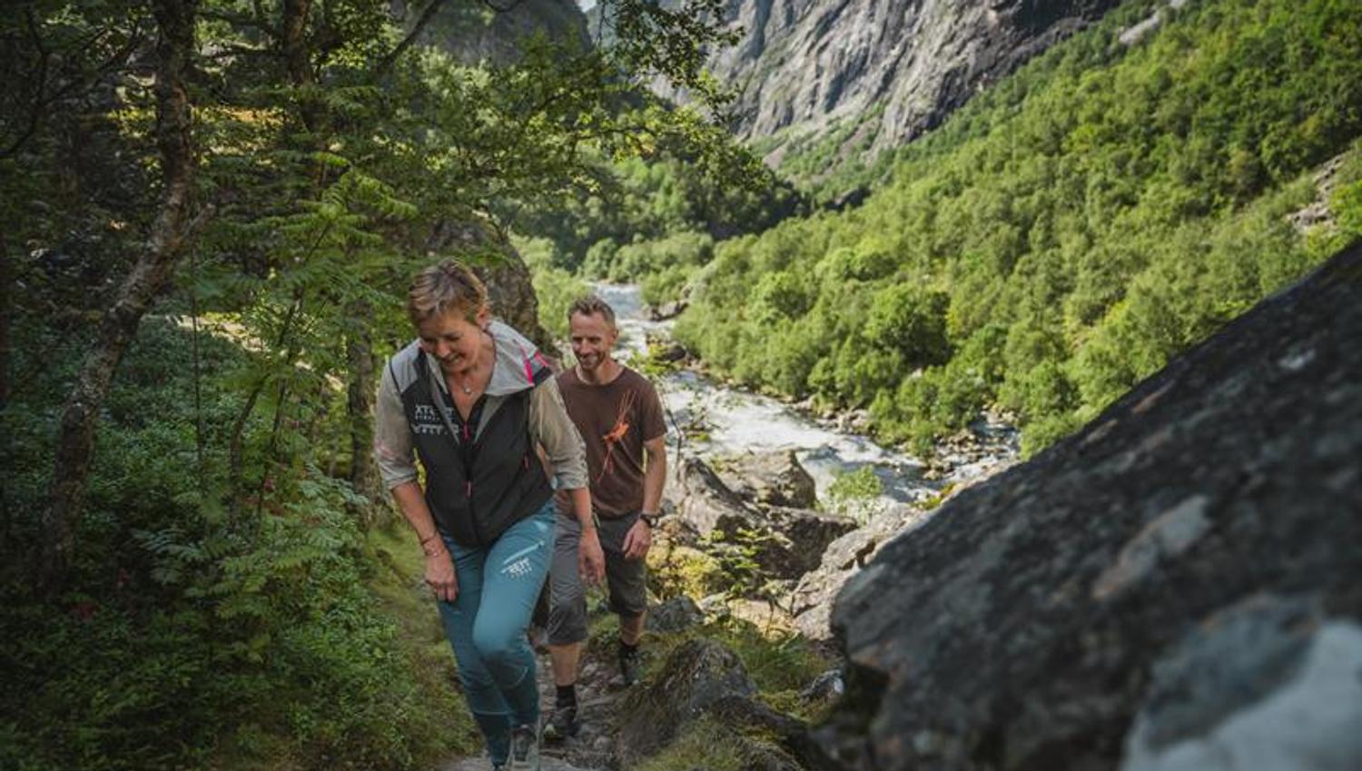 Three hikers on the path towards the new bridge below the waterfall.