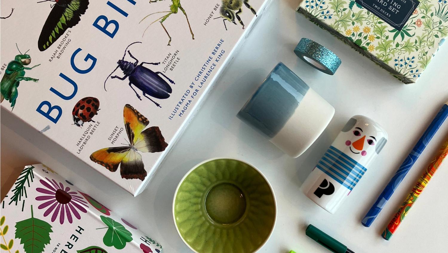A selection of items from the museum shop: games, a deck of cards, colorful cups, markers, pencils, and small gift items displayed on a table.