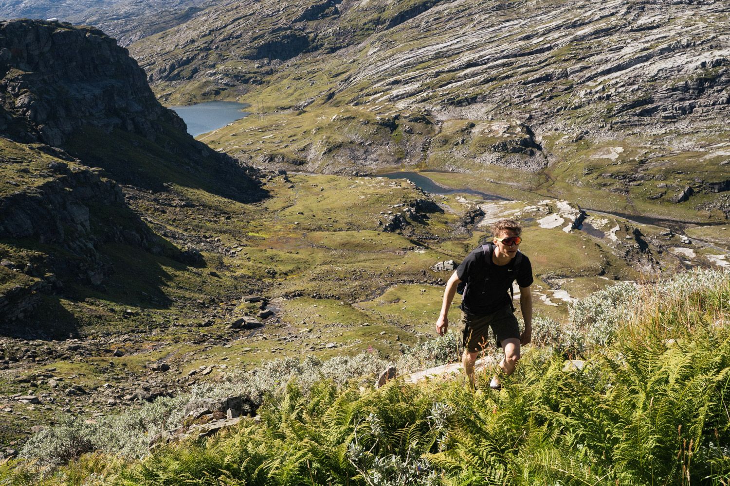 Person vandrer oppover i grønt fjellandskap.