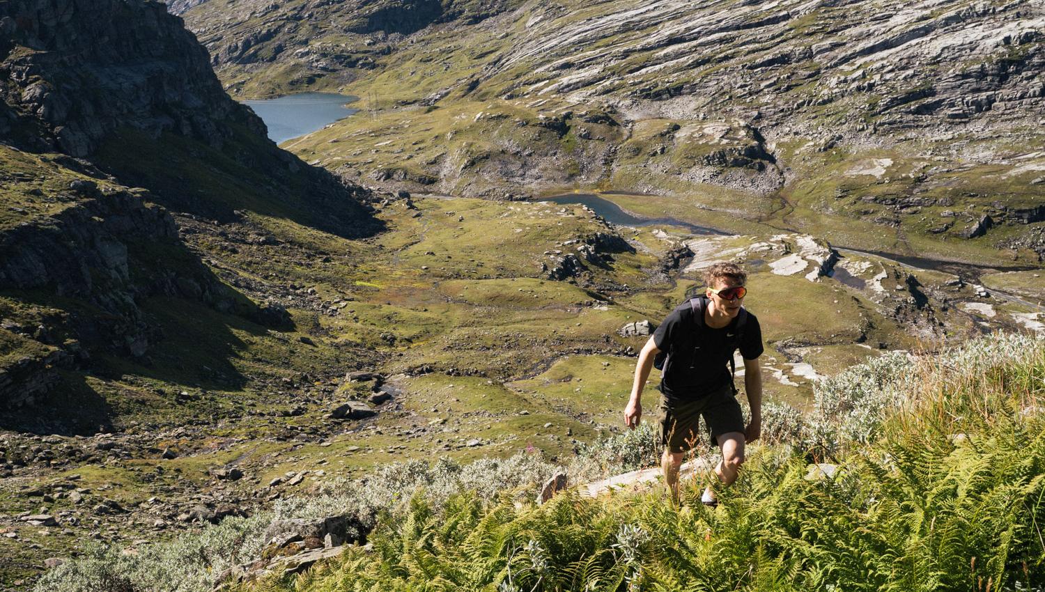 Person vandrer oppover i grønt fjellandskap.