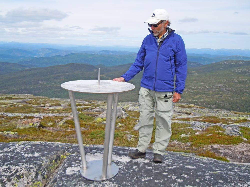 mann står ved siden av informasjonstavla på toppen av Roan