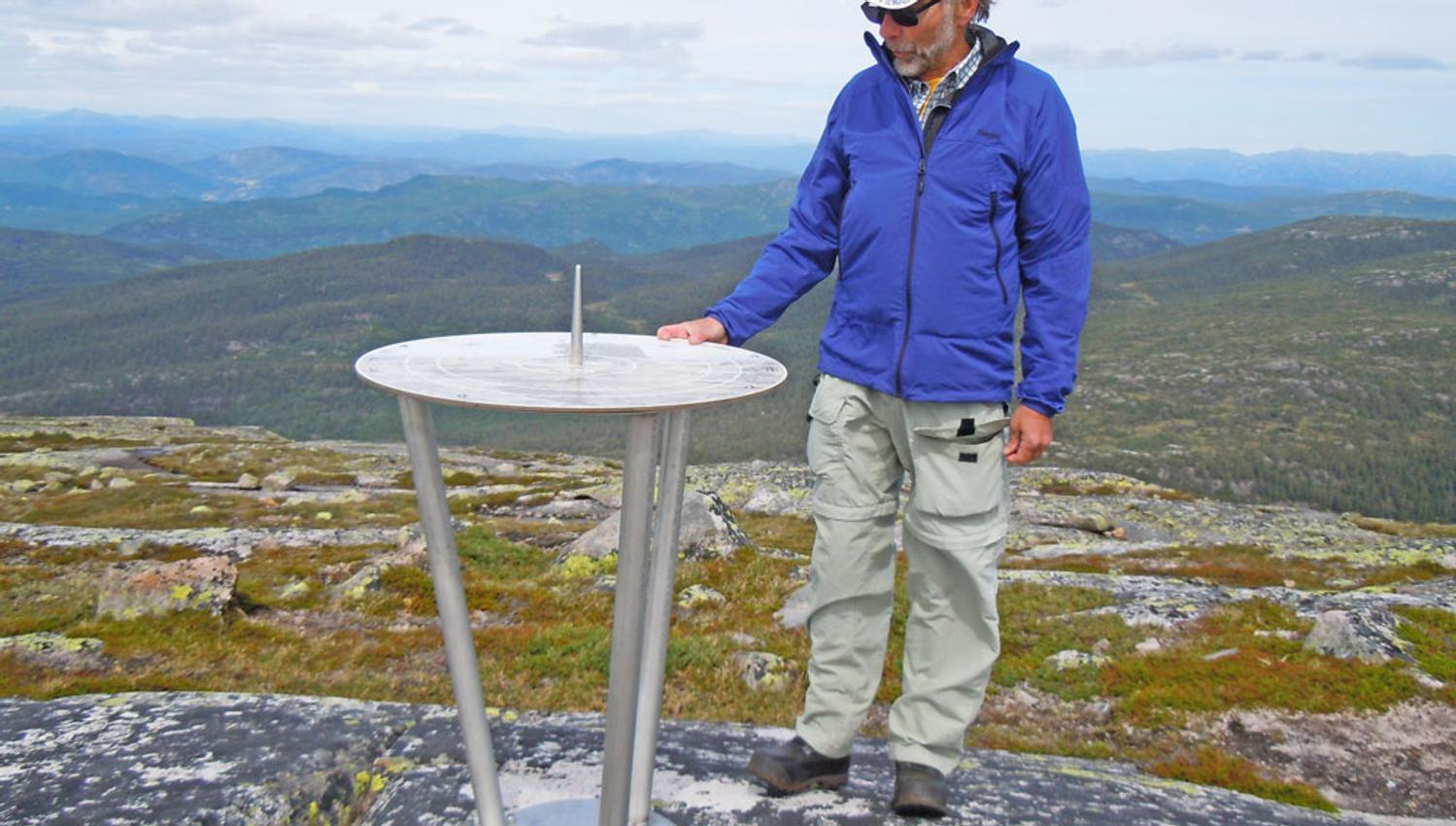 mann står ved siden av informasjonstavla på toppen av Roan